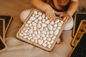 dziecko się bawi panelami sensorycznymi z kamieniami Hajo Kids