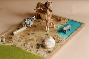 sensoryczna makieta, taca tematyczna, sensobox, rozój zmysłów dzieci, kreatywne zabawy figurkami, makieta safari, makieta afryki