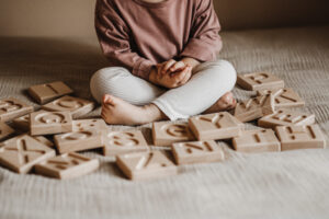 Dziecko bawi się drewnianym alfabetem żłobionym