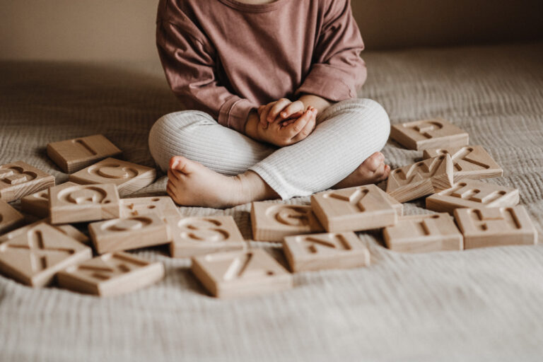 Dziecko bawi się drewnianym alfabetem żłobionym