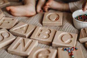 DZIdziecko wysypuje ziarna na drewnianym złobionym alfabecie ruchomym