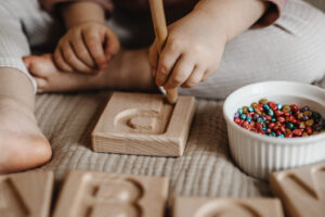 dziecko wodzi patykiem po żłobionym alfabecie