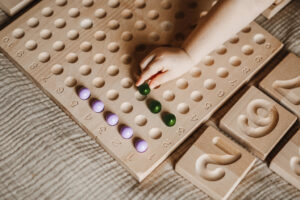 dziecko ćwiczy liczenia na tablicy do liczenia z drewna z użyciem drewnianych kulek