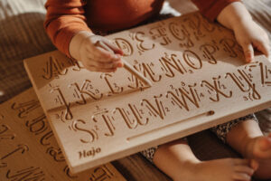 Dziecko się uczy pisać liter na tablicy grafomotorycznej z literami 