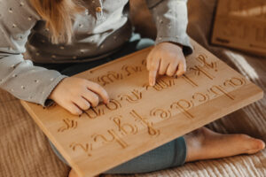 Dziecko ćwiczy pisanie liter na tablicy grafomotorycznej Hajo Kids