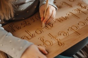 Drewniany alfabet żłobiony litery pisane małe firmy Hajo Kids w formie tablicy grafomotorycznej dla dzieci