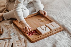 Jak dobrać zabawki Montessori do wieku dziecka – drewniana tablica do liczenia i grafomotoryka