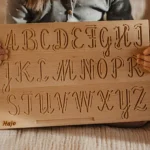 dziecko z tablicą grafomotoryczną z alfabetem pisanym