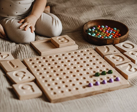 dziecko uczy sić liczyć dzieki drewnianym pomocom eduukacyjnym
