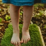 dziecko chodzi po drewnianych panelach sensorycznych boso