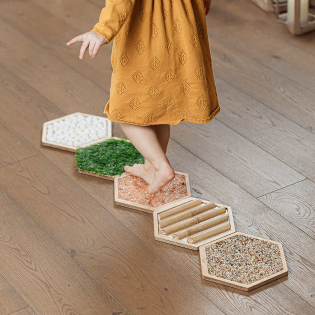 Dziecko idzie boso po ścieżce sensorycznej z trawą II STEPS